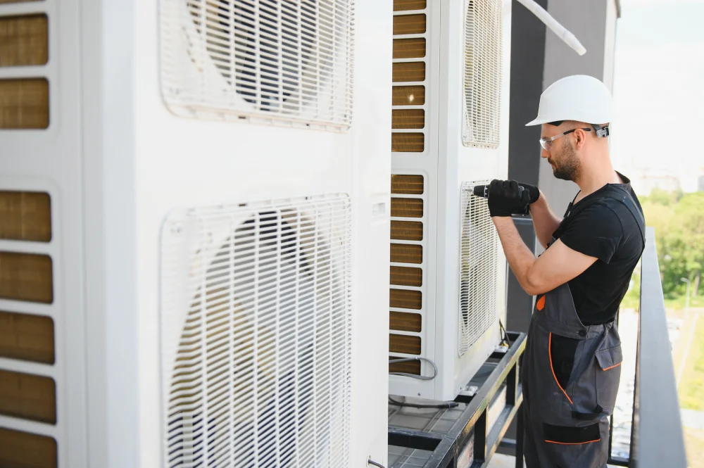technician working on air conditioning or heat pump outdoor unit. HVAC service, maintenance and repair.